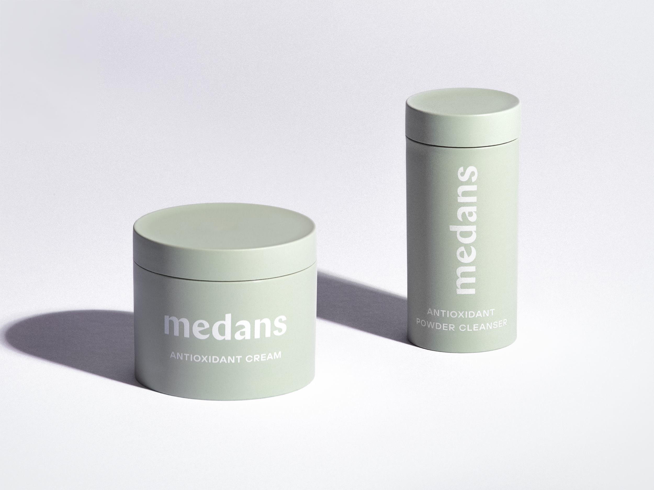Two containers of medans skincare products on a light gray background